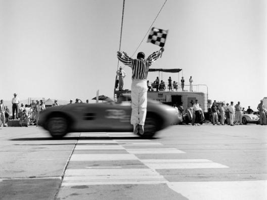 Man jumping waving checkered flag